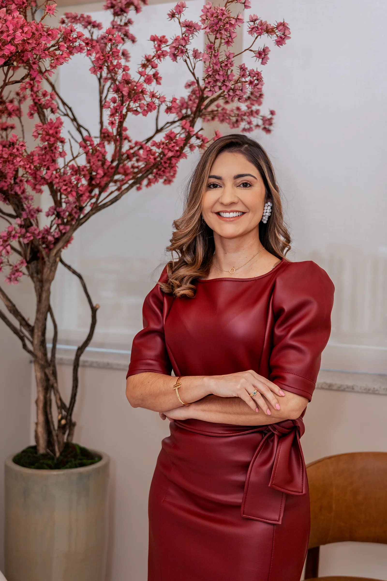 Dra. Thâmara Morita no consultório, diante da cerejeira da sala de espera